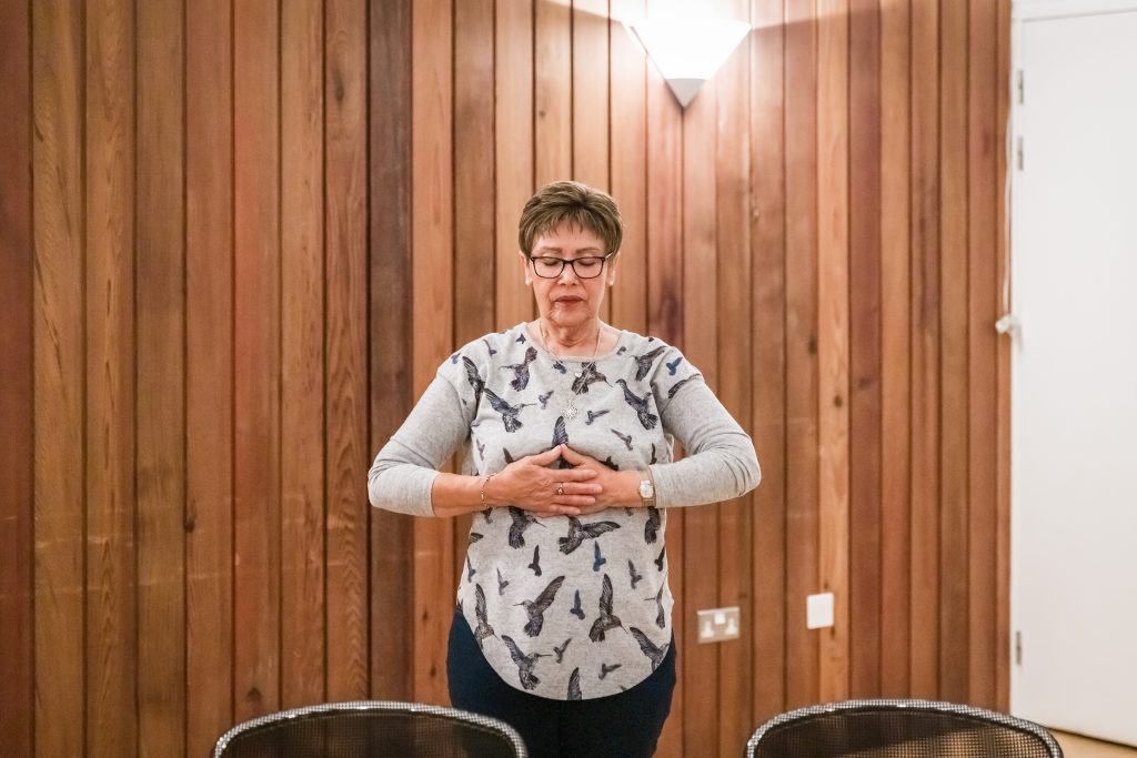 A participant stands with their eyes closed and their hands pressed on their diaphragm at breathe and connect. darts at The Point in Doncaster.