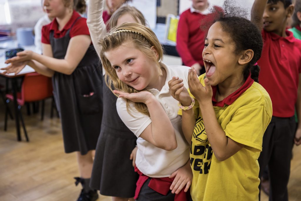A group of children wearing red and white school uniforms are taking part in an activity with darts in Doncaster.