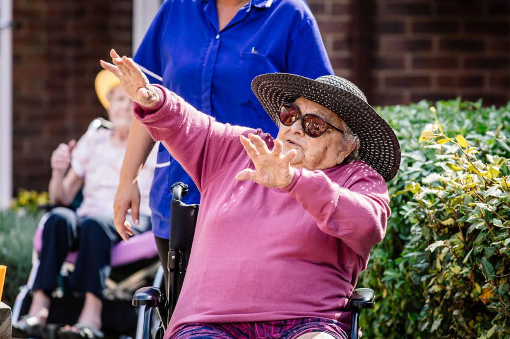 An older woman dances while seated in a wheelchair.