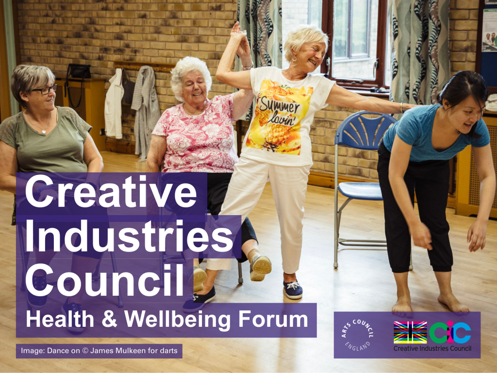 Four women of varying ages are taking part in a Dance On session in a brightly lit room with brick walls. Three older women are seated and the dance artist is standing stretching forward. Overlaid text on the left reads 